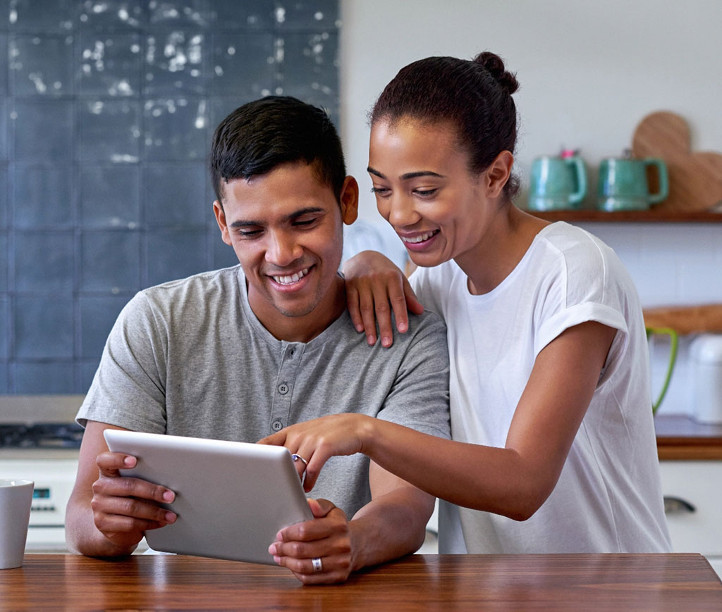 Happy couple smiling while using tablet device