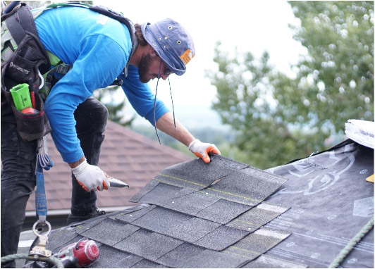 Roofer cutting shingles
