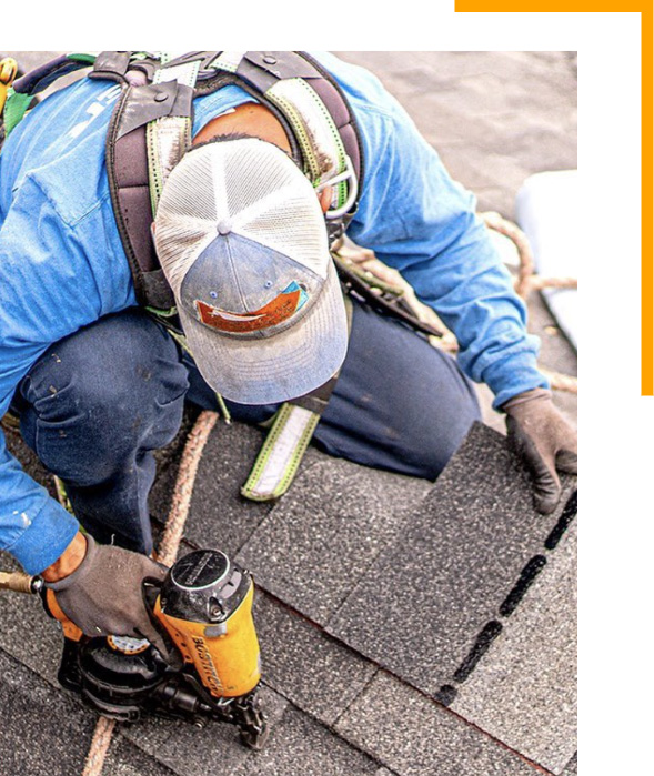 Roofer installing shingles with nailgun