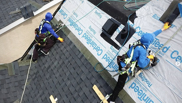Roofing team installing shingles