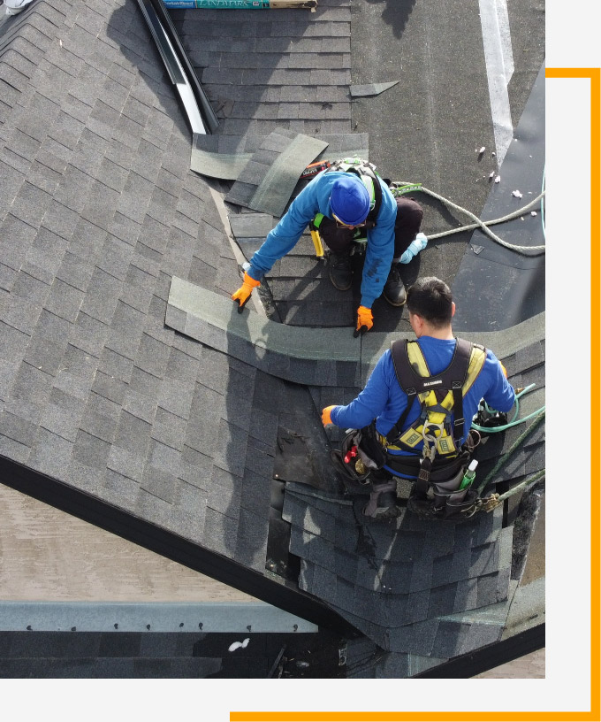 Two roofers replacing shingles