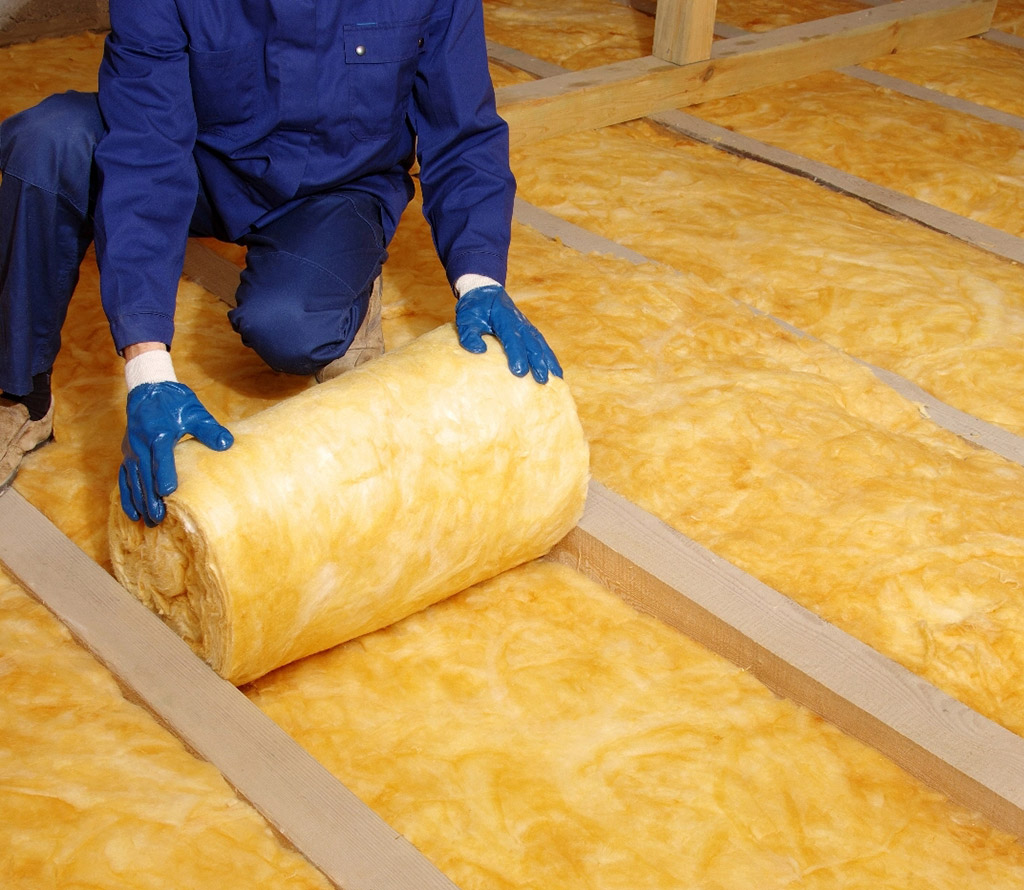 Unrolling fibre glass insulation in attic